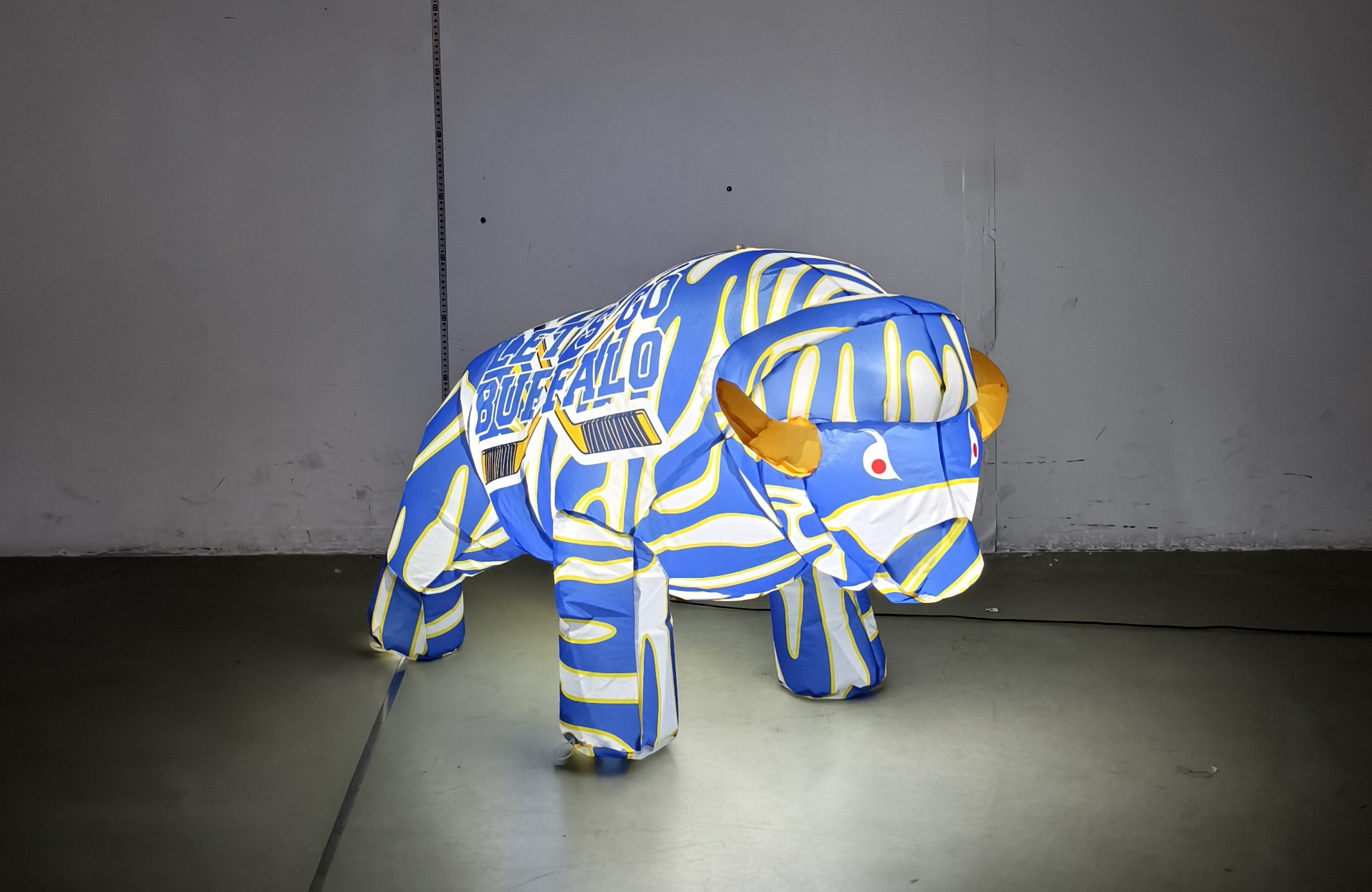 Blue, white and gold baby buffalo hockey inflatable lit up at night, front angle